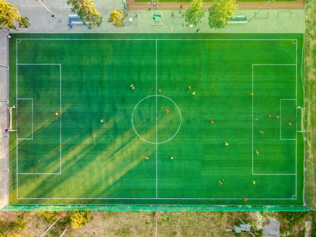 Current image: Aerial shot of a soccer game with players on a vibrant green field.